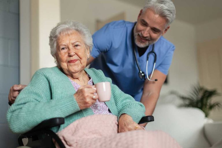 A senior person using a walker on a well-lit indoor hallway with handrails, wearing non-slip shoes.